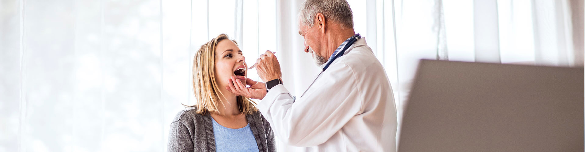 Seguro de Salud - Doctor senior examinando a una joven mujer en su consulta médica