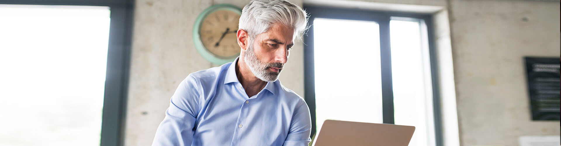 Servicio de Valores Online - Hombre de negocios sentado con su portatil en la oficina Servicio de Valores Online - Hombre de negocios sentado con su portatil en la oficina