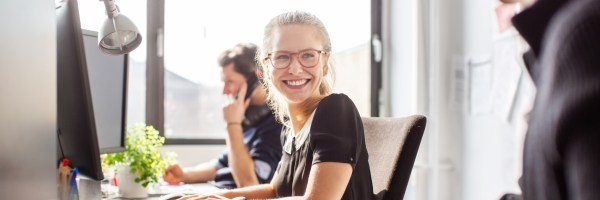 mujer-joven-feliz-sonriendo-y-mirando-a-su-companero-de-trabajo-en-la-oficina