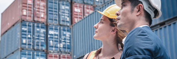 Créditos documentarios de exportación - hombre y mujer con casco rodeados de contenedores