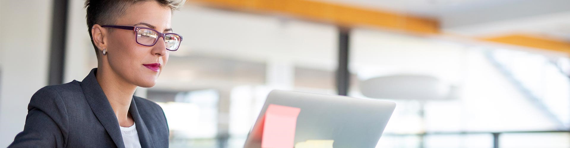 Pagos Autónomos - Una mujer con pelo corto y gafas trabajando con su portátil en la oficina buscado formas de pago Pagos Autónomos - Una mujer con pelo corto y gafas trabajando con su portátil en la oficina buscado formas de pago