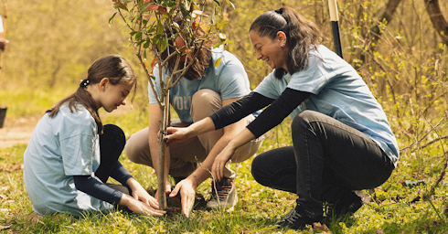 Mujeres y niña plantando árbol