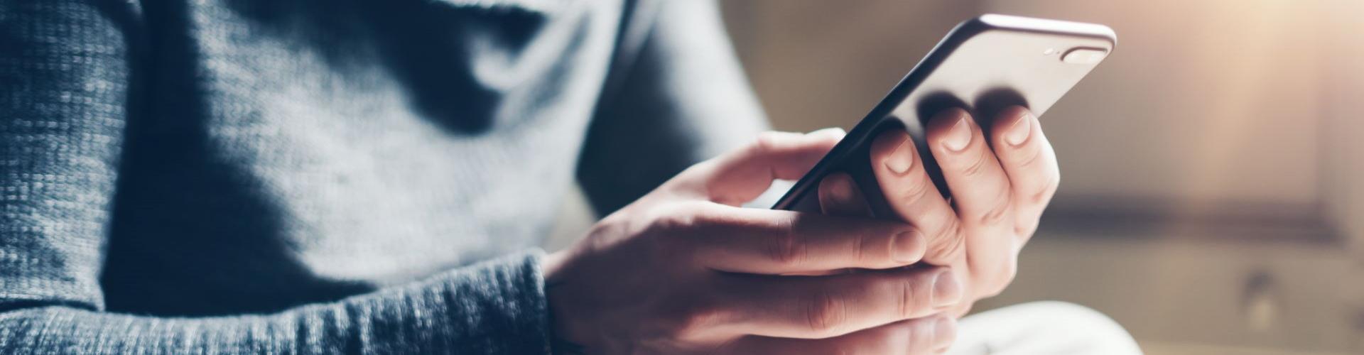 Hombre con su telefono movil en la mano. Hazte cliente de  Caja Rural con tu móvil