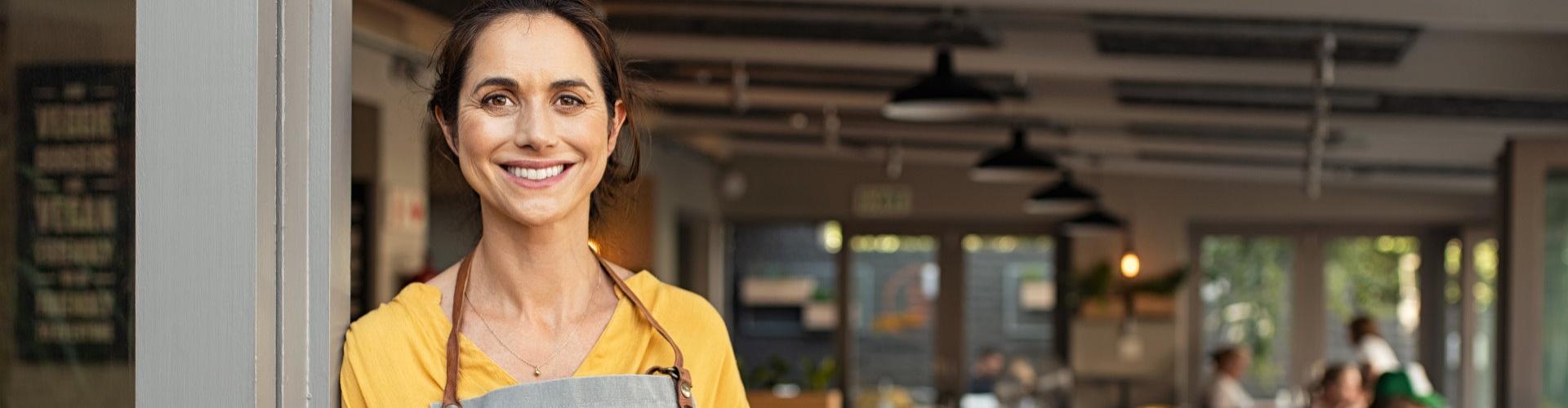 financiación autónomos - mujer sonriendo frente a su negocio - Rural Kutxa