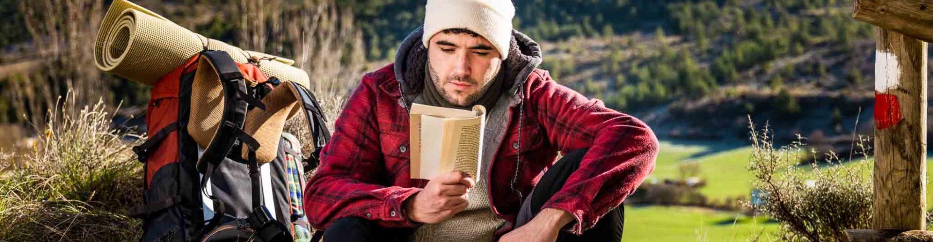 Seguro de Asistencia en Viaje - joven-mochilero-leyendo-libro