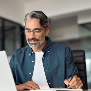 Hombre tomando notas de un portatil