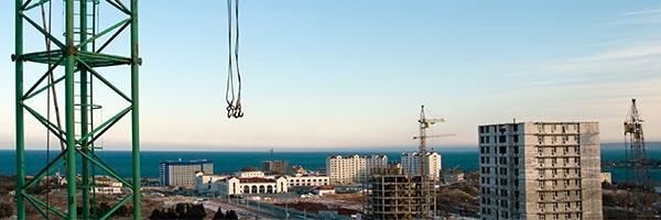 Seguro Decenal de Daños - Obra construyendo edificios con gruas, camiones y trabajadores trabajando