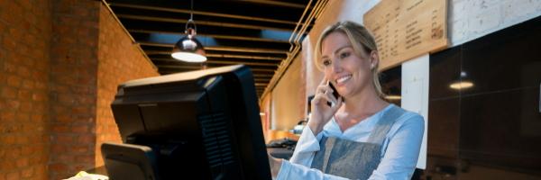 vendedora-registrar-una-orden-de-comida-para-llevar-mientras-habla-con-el-cliente-en-un-smartphone-de-aspecto-feliz.-restaurante.-delivery.-pedido-a-domicilio