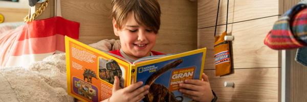 Ahorra con la libreta en marcha - Niño leyendo tbo en su cuarto Ahorra con la libreta en marcha - Niño leyendo tbo en su cuarto