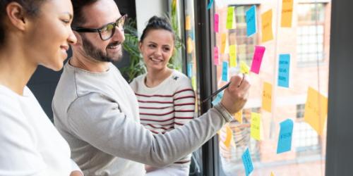 Guía Práctica para Emprender - Mujeres y hombre pensando en oficina señalando post it en cristal - Rural Kutxa