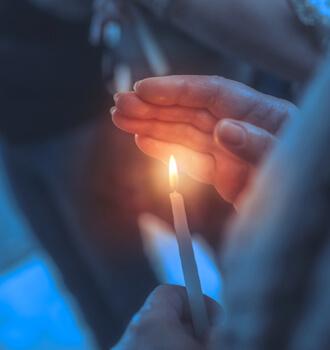 Entidades religiosas - Persona rezando en una entidad religiosa con una vela en la mano