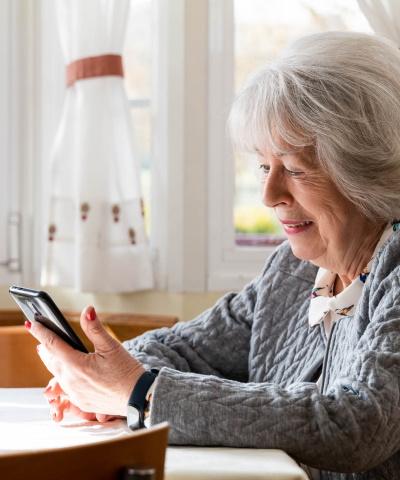 Cuenta online ruralvía - Mujer sonriendo sentada utilizando un móvil