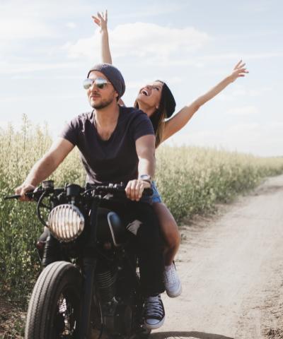 Seguro del Automóvil - Pareja joven feliz en su moto conduciendo por un camino